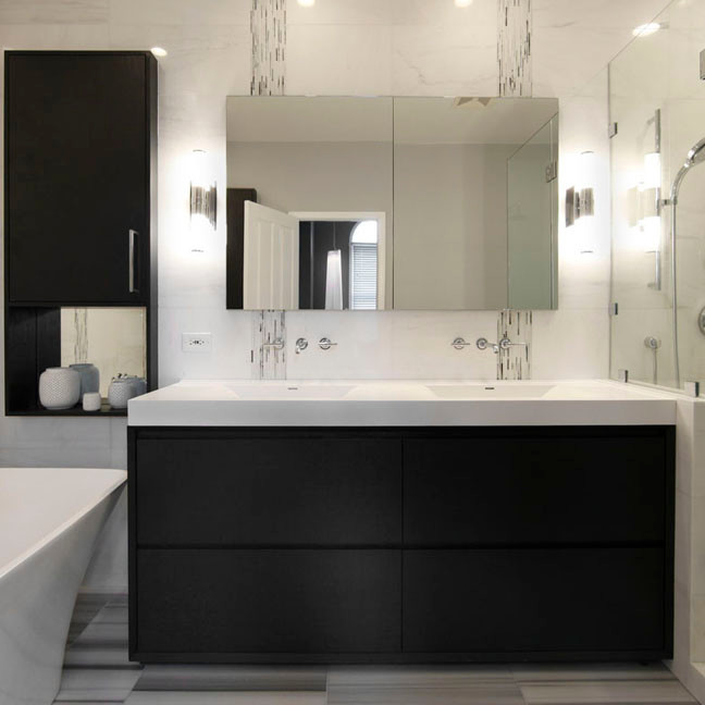 Foto på ett badrum, med ett integrerad handfat, skåp i mörkt trä, ett fristående badkar, vit kakel och vita väggar