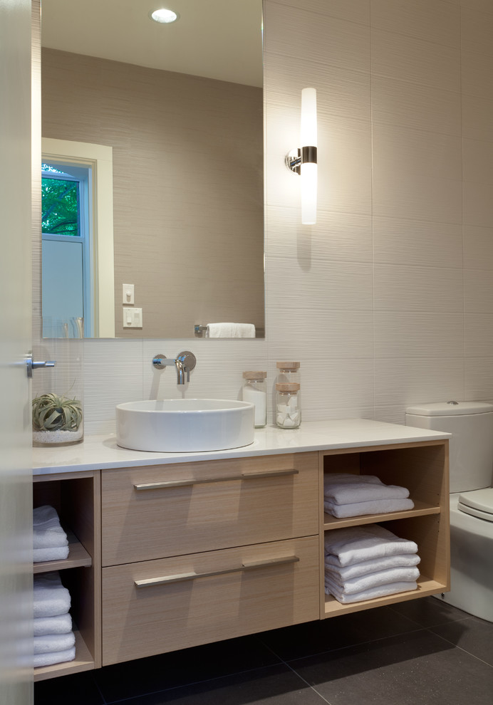 Modelo de cuarto de baño actual con lavabo sobreencimera, armarios abiertos, puertas de armario de madera clara y baldosas y/o azulejos beige