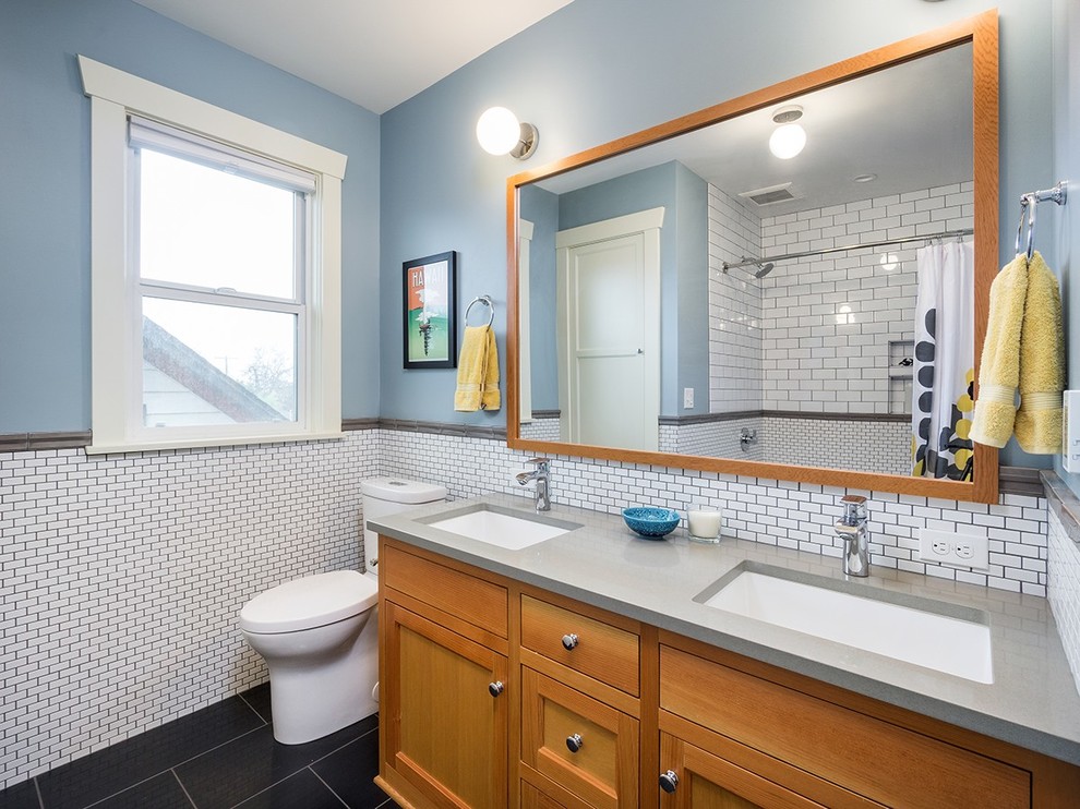 Example of a mid-sized transitional 3/4 white tile and porcelain tile porcelain tile and black floor bathroom design in Portland with shaker cabinets, medium tone wood cabinets, a two-piece toilet, blue walls, an undermount sink and solid surface countertops
