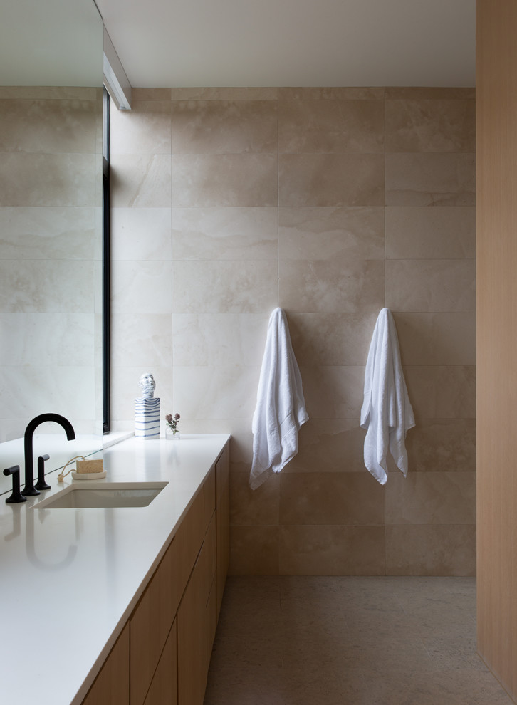 Exemple d'une grande salle de bain principale moderne en bois clair avec un carrelage beige, du carrelage en pierre calcaire, un mur beige, un sol en calcaire, un lavabo encastré, un plan de toilette en quartz, un sol beige, une cabine de douche à porte battante et un plan de toilette blanc.