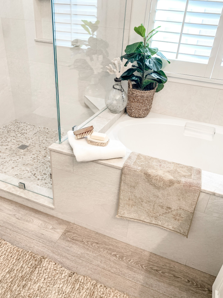 Inspiration for a medium sized beach style ensuite bathroom in Orange County with shaker cabinets, white cabinets, a submerged bath, a corner shower, beige tiles, porcelain tiles, white walls, light hardwood flooring, a built-in sink, quartz worktops, a hinged door, beige worktops, a shower bench, double sinks and a built in vanity unit.
