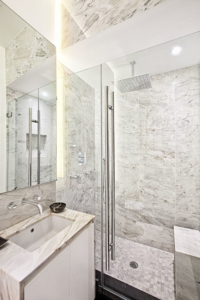 Пример оригинального дизайна: ванная комната в современном стиле с врезной раковиной, плоскими фасадами, белыми фасадами, серой плиткой и каменной плиткой