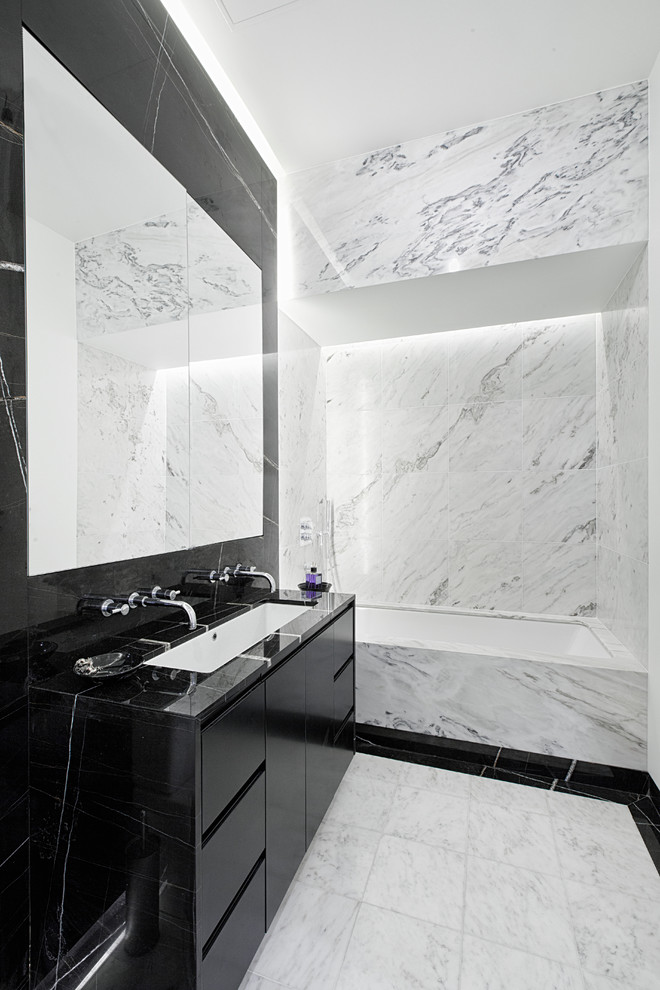 Свежая идея для дизайна: ванная комната в современном стиле с раковиной с несколькими смесителями, плоскими фасадами, черными фасадами, ванной в нише, черной плиткой и плиткой из листового камня - отличное фото интерьера