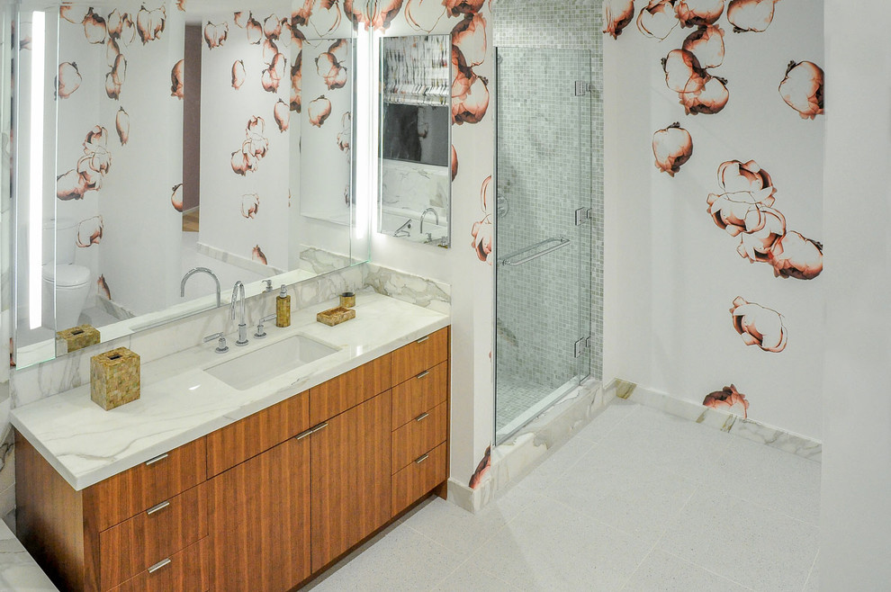 На фото: большая главная ванная комната в современном стиле с плоскими фасадами, фасадами цвета дерева среднего тона, душем в нише, унитазом-моноблоком, белой плиткой, плиткой мозаикой, разноцветными стенами, полом из мозаичной плитки, врезной раковиной и столешницей из известняка с