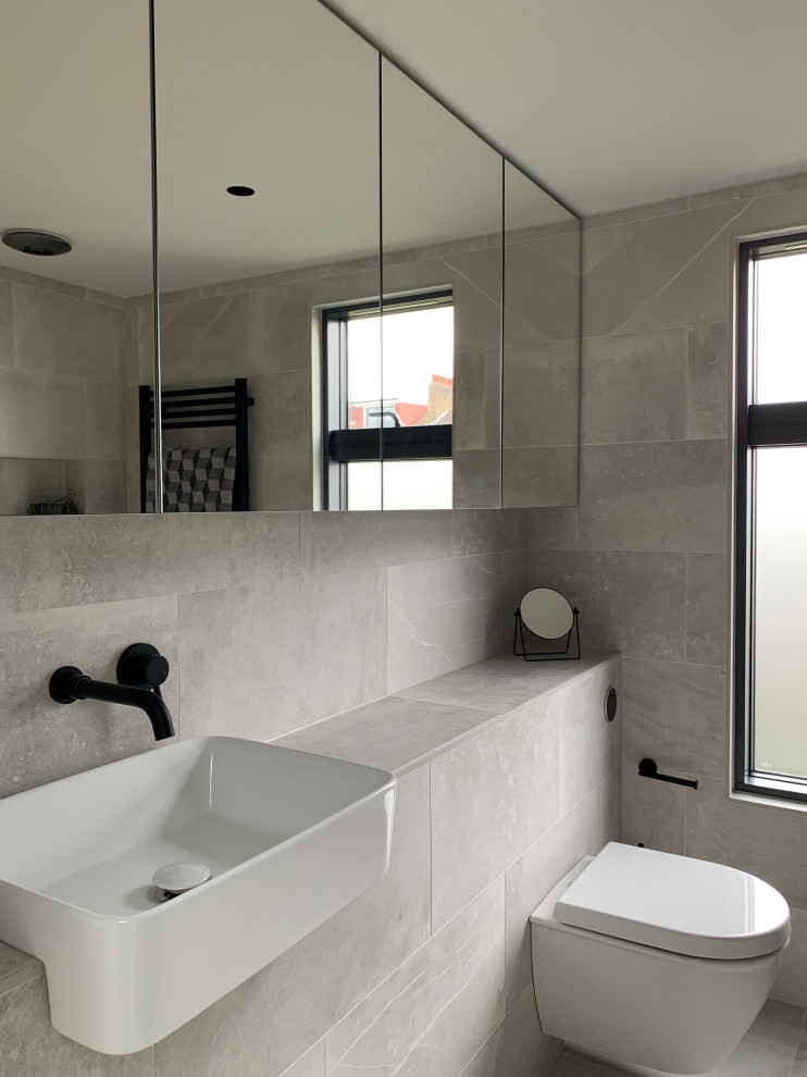 Design ideas for a small modern shower room bathroom in London with glass-front cabinets, a walk-in shower, a wall mounted toilet, grey tiles, porcelain tiles, grey walls, porcelain flooring, a built-in sink, tiled worktops, grey floors, an open shower, grey worktops, a single sink and a built in vanity unit.