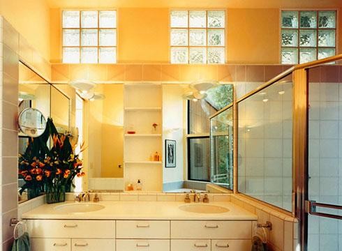 На фото: главная ванная комната среднего размера в классическом стиле с плоскими фасадами, белыми фасадами, угловым душем, бежевой плиткой, плиткой из известняка, монолитной раковиной, столешницей из искусственного кварца, душем с распашными дверями и белой столешницей с
