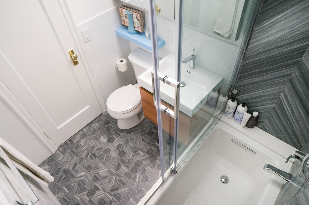 Immagine di una stanza da bagno padronale design di medie dimensioni con ante lisce, vasca da incasso, WC a due pezzi, piastrelle grigie, piastrelle in pietra, pareti bianche, pavimento in marmo e lavabo sospeso