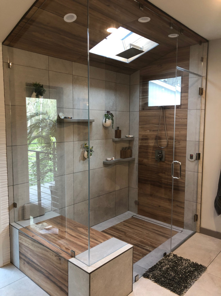 Photo of a medium sized world-inspired ensuite bathroom in San Francisco with recessed-panel cabinets, brown cabinets, a corner shower, a two-piece toilet, beige tiles, ceramic tiles, beige walls, ceramic flooring, a built-in sink, quartz worktops, multi-coloured floors, a hinged door, grey worktops, a shower bench, a single sink, a floating vanity unit, a vaulted ceiling and wallpapered walls.