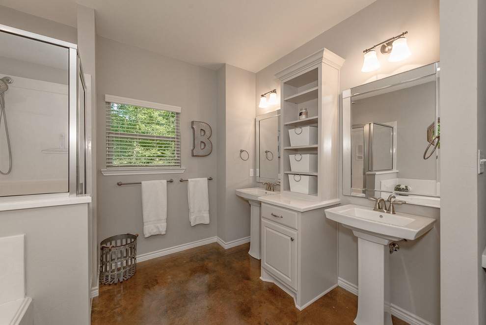 Inspiration for a medium sized traditional ensuite bathroom in Austin with shaker cabinets, white cabinets, a corner bath, an alcove shower, a two-piece toilet, white tiles, metro tiles, grey walls, concrete flooring, a pedestal sink, solid surface worktops, brown floors and a hinged door.
