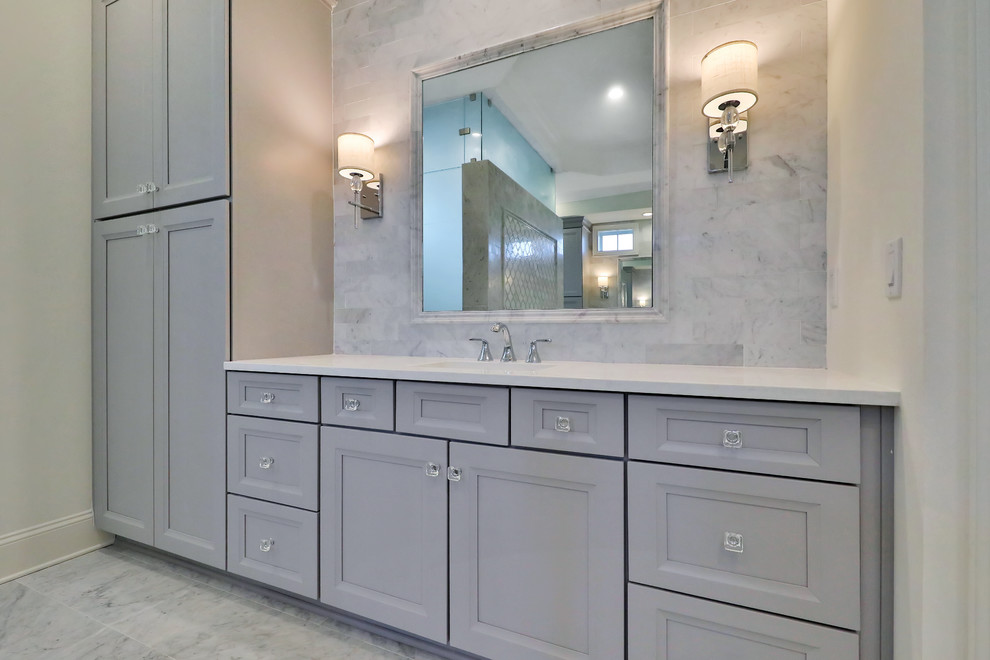 Large beach style ensuite bathroom in Jacksonville with raised-panel cabinets, grey cabinets, a built-in bath, marble tiles, marble flooring, a submerged sink, engineered stone worktops, a hinged door and white worktops.