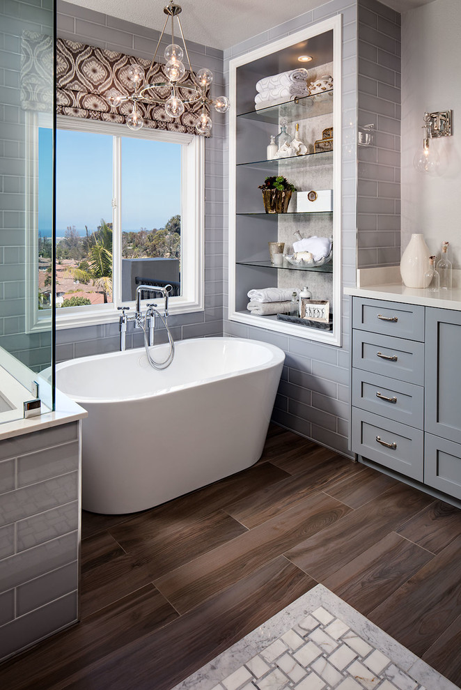 Imagen de cuarto de baño principal tradicional renovado con puertas de armario grises, bañera exenta, baldosas y/o azulejos de cemento y suelo de madera en tonos medios