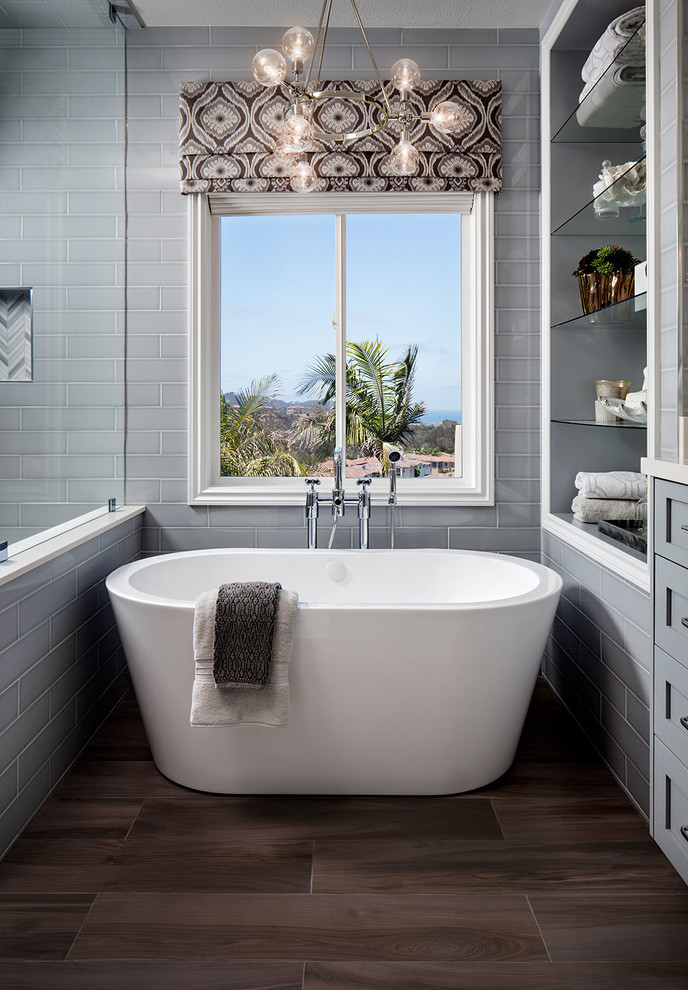 Klassisches Badezimmer En Suite mit grauen Schränken, freistehender Badewanne, grauen Fliesen, Metrofliesen und braunem Holzboden in San Diego