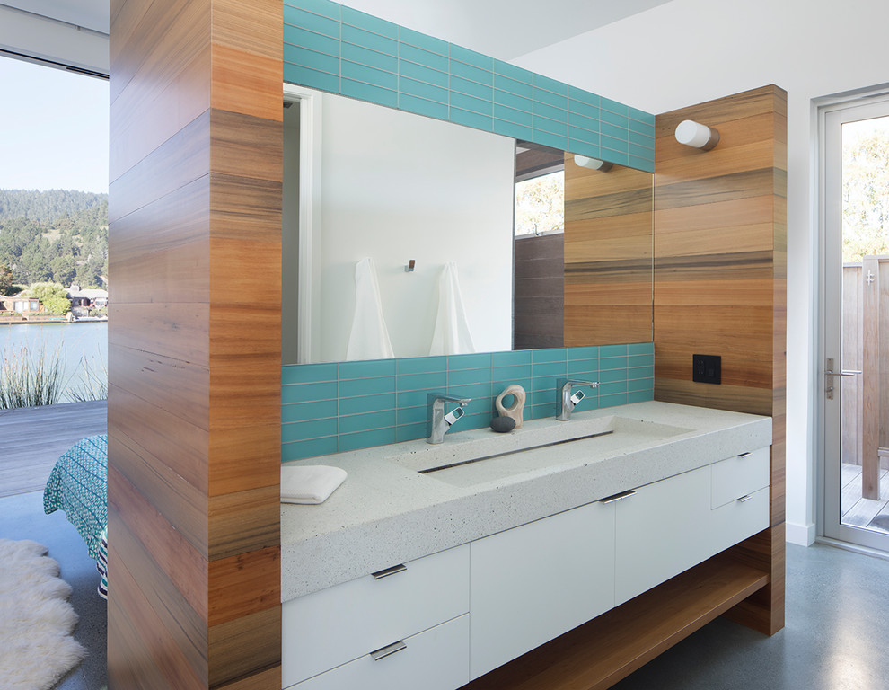 This is an example of a coastal ensuite bathroom in San Francisco with white cabinets, blue tiles, glass tiles, concrete worktops, flat-panel cabinets, white walls, concrete flooring, a trough sink, grey floors and grey worktops.