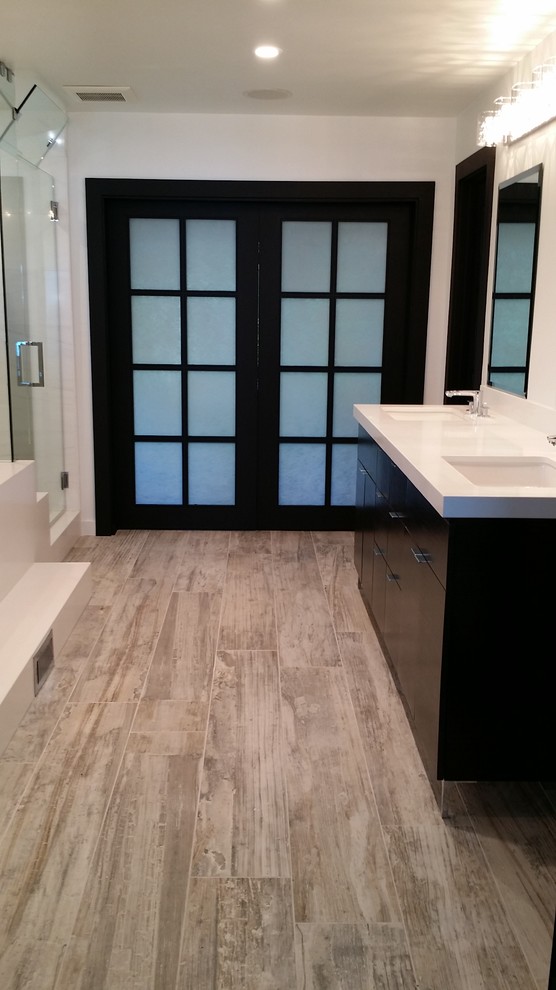 Photo of a large modern ensuite bathroom in Orange County with flat-panel cabinets, dark wood cabinets, an alcove shower, a two-piece toilet, porcelain flooring, a submerged sink, engineered stone worktops, grey floors, a hinged door, white worktops, a built-in bath, white tiles, marble tiles and white walls.