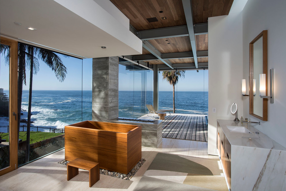 Cette image montre une salle de bain principale design en bois brun avec un placard à porte plane, un lavabo encastré et un bain japonais.