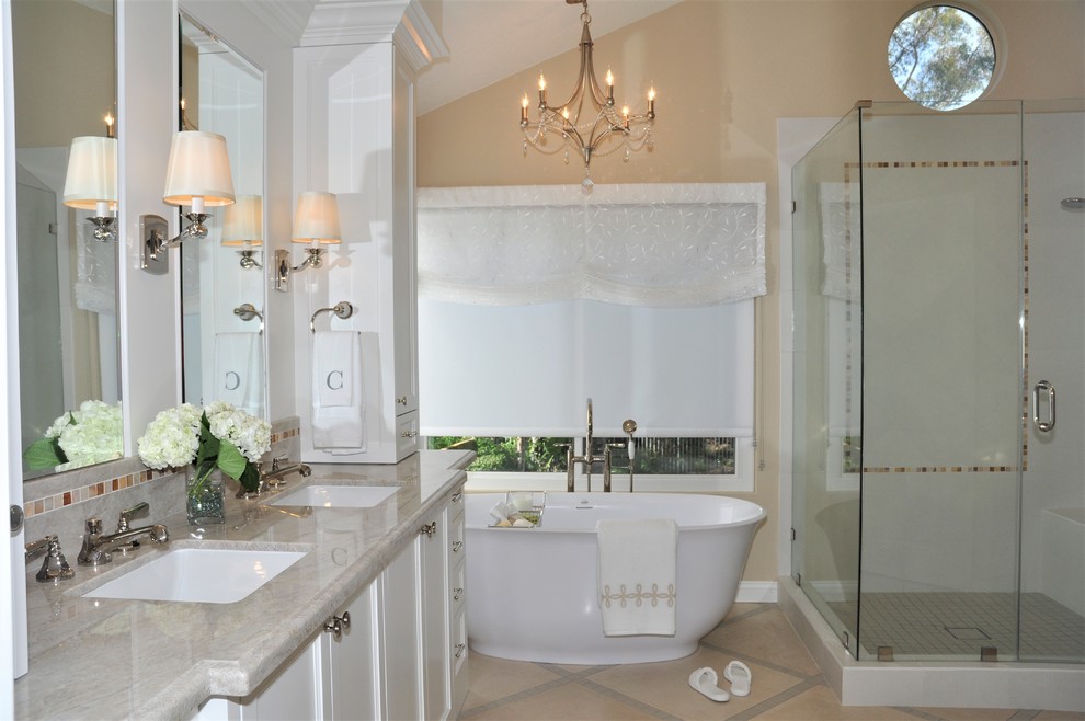Inspiration for a medium sized traditional ensuite bathroom in Orange County with a freestanding bath, a corner shower, a one-piece toilet, white tiles, porcelain tiles, beige walls, limestone flooring, a submerged sink, quartz worktops, beige floors, a hinged door, shaker cabinets, beige worktops, double sinks, a built in vanity unit and white cabinets.