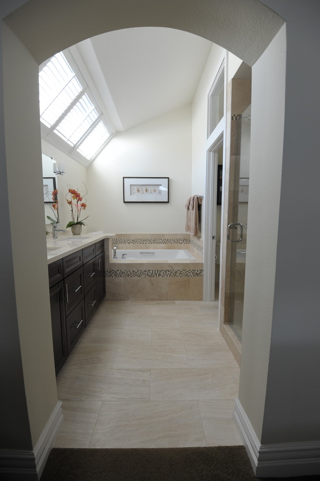 Photo of a medium sized contemporary ensuite bathroom in Orange County with a submerged sink, shaker cabinets, dark wood cabinets, engineered stone worktops, a built-in bath, a one-piece toilet, beige tiles, stone tiles and travertine flooring.
