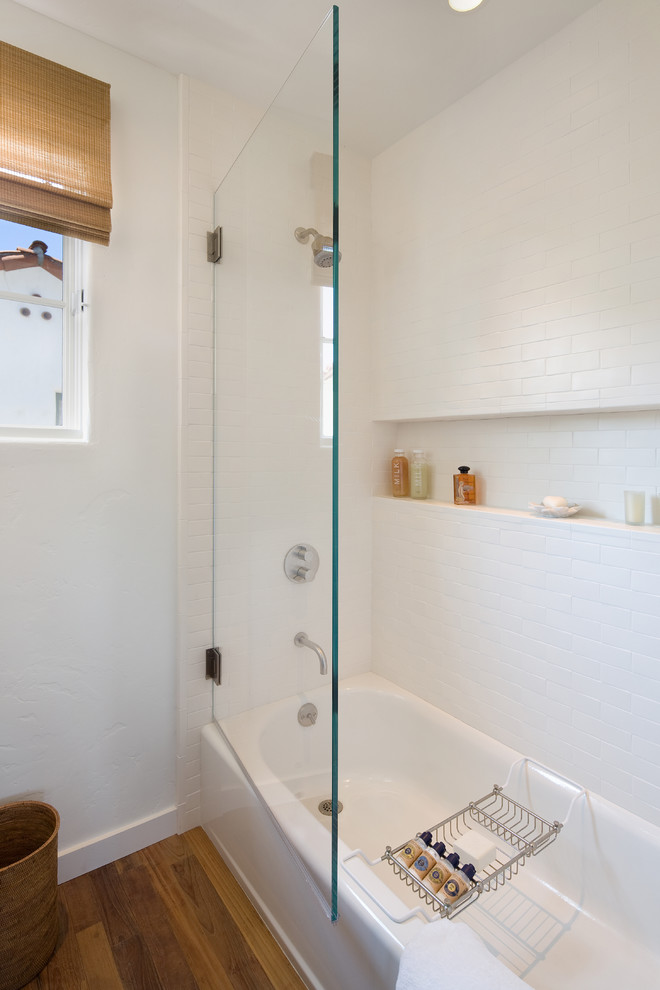 Идея дизайна: главная ванная комната среднего размера в средиземноморском стиле с раковиной с несколькими смесителями, ванной в нише, душем над ванной, унитазом-моноблоком, белой плиткой, керамической плиткой, белыми стенами и паркетным полом среднего тона