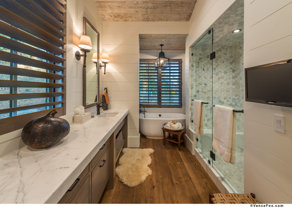 Photo of a large traditional ensuite bathroom in Other with light wood cabinets, a freestanding bath, an alcove shower, white tiles, white walls, light hardwood flooring, a built-in sink, marble worktops, brown floors and a hinged door.