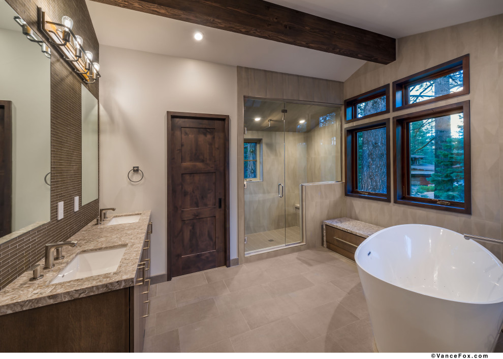 Cette image montre une salle de bain chalet avec une baignoire indépendante, un lavabo encastré et une cabine de douche à porte battante.