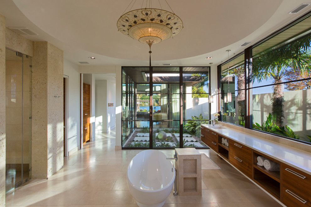 Design ideas for a medium sized contemporary ensuite bathroom in Austin with a submerged sink, flat-panel cabinets, medium wood cabinets, engineered stone worktops, a freestanding bath, a built-in shower, a one-piece toilet, beige tiles, stone tiles, beige walls and limestone flooring.