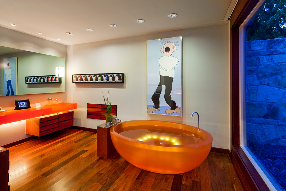 На фото: большая главная ванная комната в стиле фьюжн с отдельно стоящей ванной, бежевыми стенами, темным паркетным полом, раковиной с несколькими смесителями, коричневым полом и оранжевой столешницей