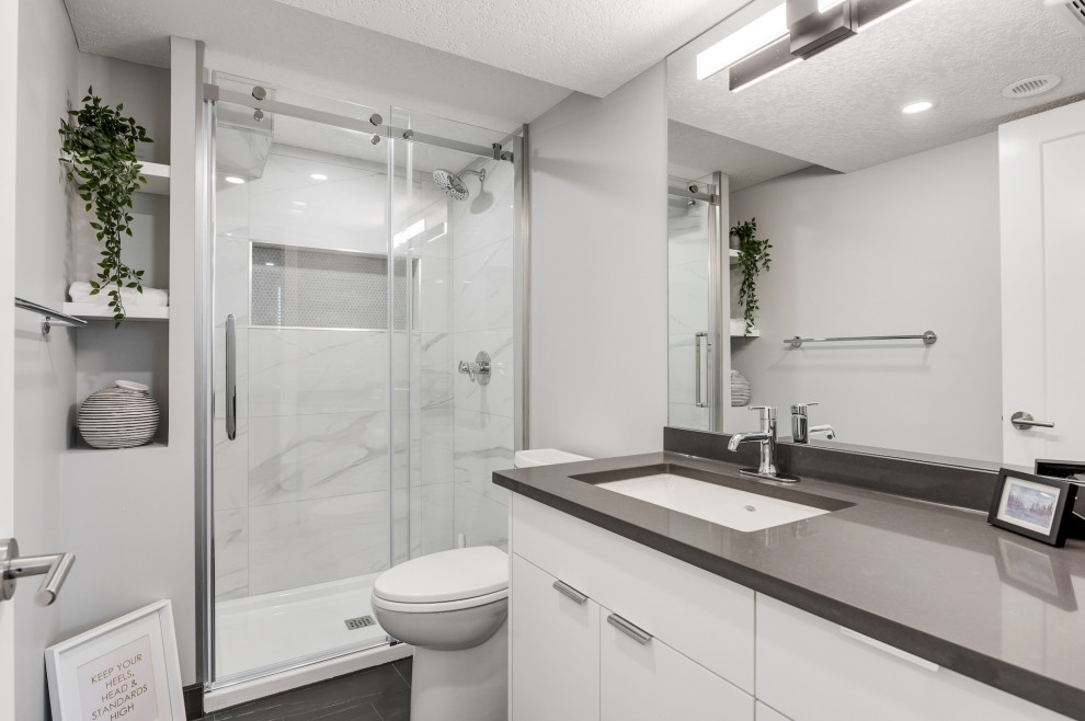 Bathroom - small contemporary black and white tile and porcelain tile porcelain tile, black floor and single-sink bathroom idea in Calgary with white cabinets, a two-piece toilet, gray walls, an undermount sink, quartz countertops, gray countertops, a niche and a built-in vanity
