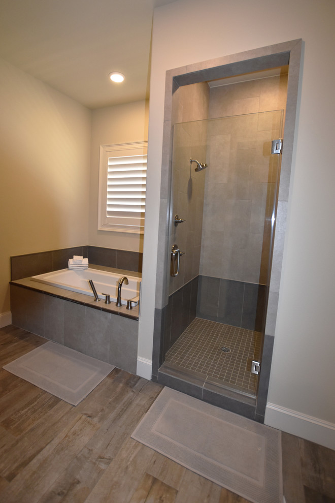 Large mediterranean family bathroom in Houston with raised-panel cabinets, grey cabinets, a built-in bath, an alcove shower, a two-piece toilet, grey tiles, porcelain tiles, beige walls and porcelain flooring.