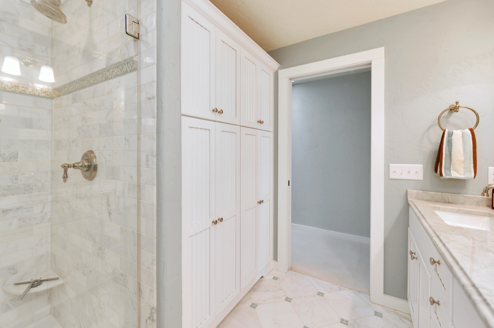Ispirazione per una stanza da bagno stile marinaro con lavabo sottopiano, ante bianche, top in marmo, piastrelle in pietra e pavimento in marmo
