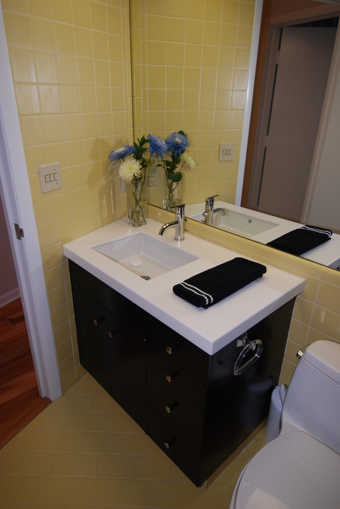 Пример оригинального дизайна: маленькая ванная комната в стиле модернизм с врезной раковиной, плоскими фасадами, черными фасадами, столешницей из искусственного кварца, ванной в нише, душем над ванной, унитазом-моноблоком, желтой плиткой, керамической плиткой, желтыми стенами и полом из керамической плитки для на участке и в саду