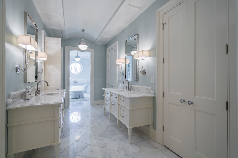 Diseño de cuarto de baño principal y rectangular clásico con puertas de armario blancas, bañera exenta, paredes azules, lavabo bajoencimera, suelo blanco y armarios con rebordes decorativos