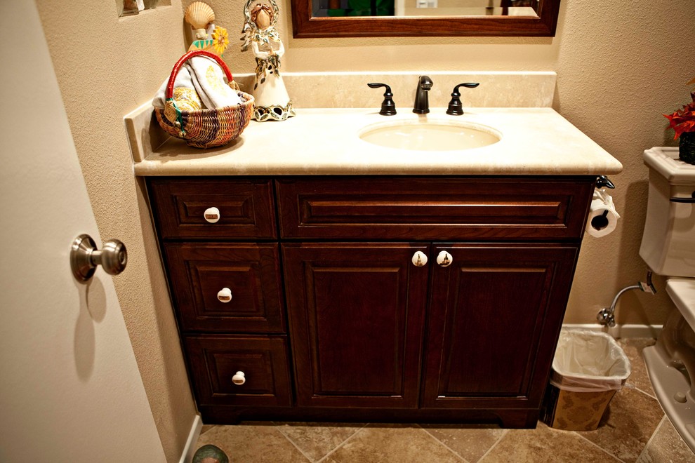 Foto på ett litet vintage badrum med dusch, med ett undermonterad handfat, luckor med upphöjd panel, skåp i mörkt trä, bänkskiva i akrylsten, en dusch i en alkov, en toalettstol med separat cisternkåpa, beige kakel, porslinskakel, beige väggar och klinkergolv i porslin