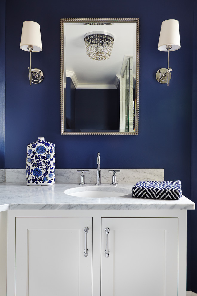 Exemple d'une grande salle de bain principale tendance avec un lavabo encastré, un placard à porte affleurante, des portes de placard blanches, un plan de toilette en marbre, une douche d'angle, un carrelage blanc et un mur bleu.