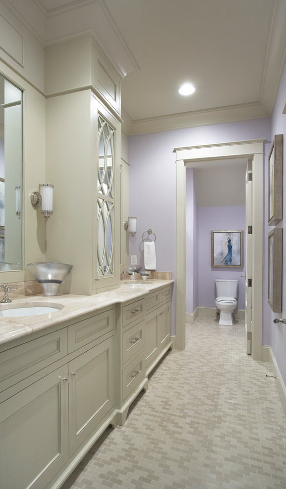 Idée de décoration pour une grande salle de bain tradition avec un lavabo encastré, un placard avec porte à panneau encastré, des portes de placard beiges, un plan de toilette en calcaire, WC séparés, un mur violet et un sol en carrelage de porcelaine.