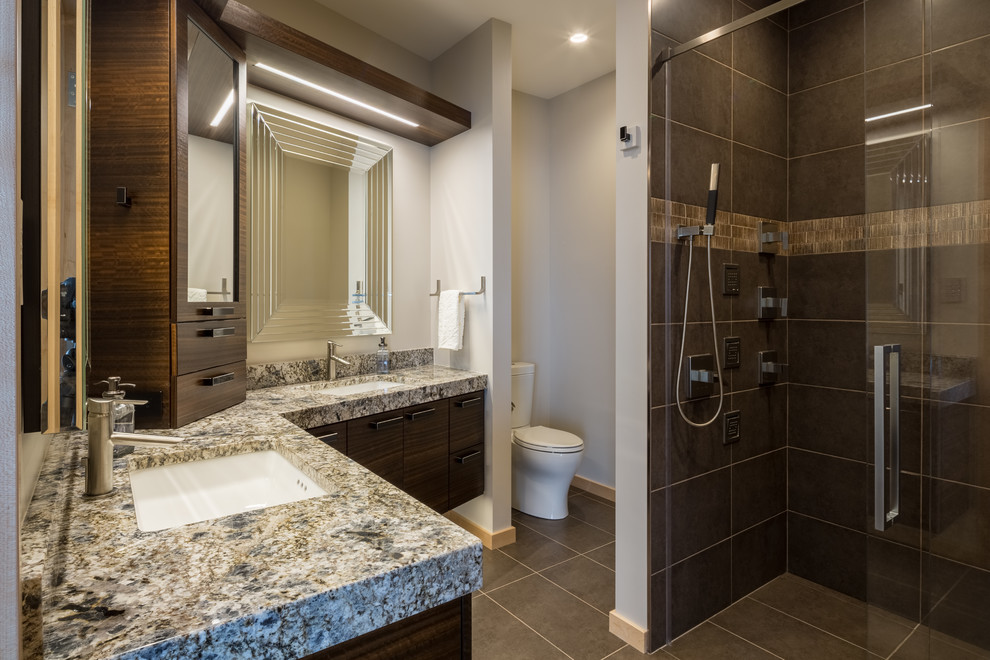 Design ideas for a medium sized contemporary ensuite bathroom in Other with flat-panel cabinets, dark wood cabinets, a built-in shower, a one-piece toilet, beige tiles, brown tiles, ceramic tiles, grey walls, slate flooring, a submerged sink and granite worktops.