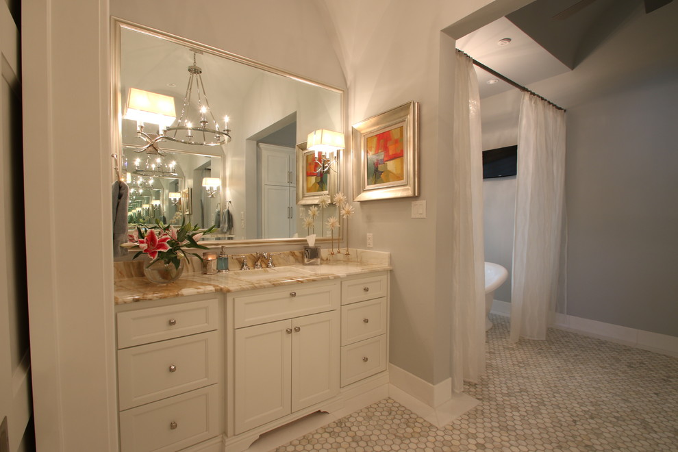 Aménagement d'une salle de bain principale classique de taille moyenne avec un placard avec porte à panneau encastré, des portes de placard blanches, une baignoire indépendante, un mur gris, un sol en marbre, un lavabo encastré et un plan de toilette en onyx.