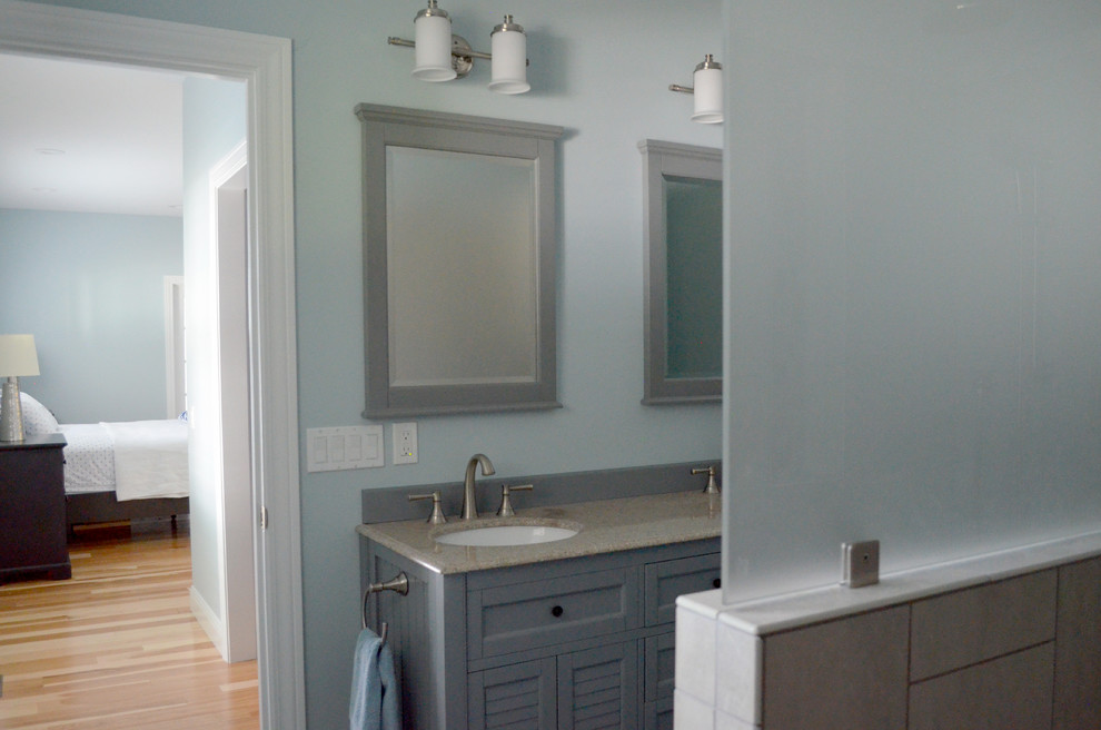 Maritim inredning av ett en-suite badrum, med luckor med lamellpanel, grå skåp, en kantlös dusch, beige kakel, blå väggar, klinkergolv i keramik, ett undermonterad handfat och bänkskiva i akrylsten