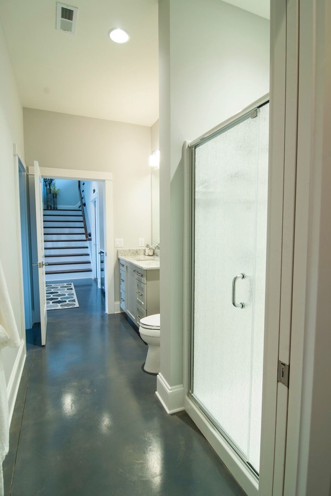 Свежая идея для дизайна: большая ванная комната в стиле неоклассика (современная классика) с белыми фасадами, душем в нише, унитазом-моноблоком, серыми стенами, бетонным полом, душевой кабиной, врезной раковиной, столешницей из гранита, коричневым полом и душем с распашными дверями - отличное фото интерьера