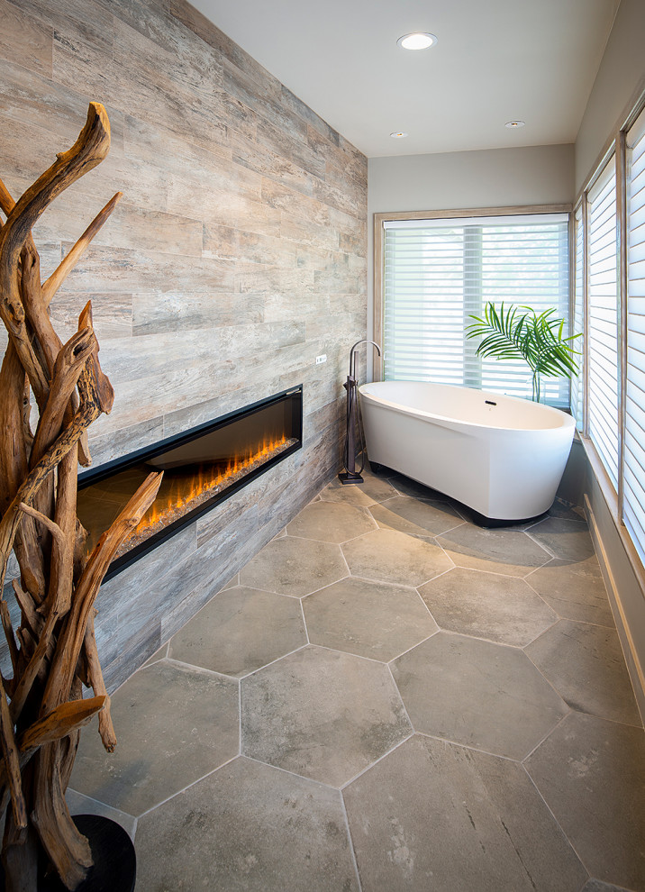 Inspiration for a coastal ensuite bathroom in Sacramento with flat-panel cabinets, beige cabinets, a freestanding bath, a double shower, a one-piece toilet, grey tiles, porcelain tiles, grey walls, porcelain flooring, a vessel sink, solid surface worktops, grey floors, a hinged door and grey worktops.