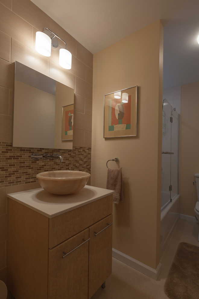 Inredning av ett eklektiskt mellanstort badrum, med ett fristående handfat, släta luckor, skåp i ljust trä, bänkskiva i kvarts, ett badkar i en alkov, en dusch/badkar-kombination, en toalettstol med separat cisternkåpa, beige kakel, porslinskakel, orange väggar och klinkergolv i porslin