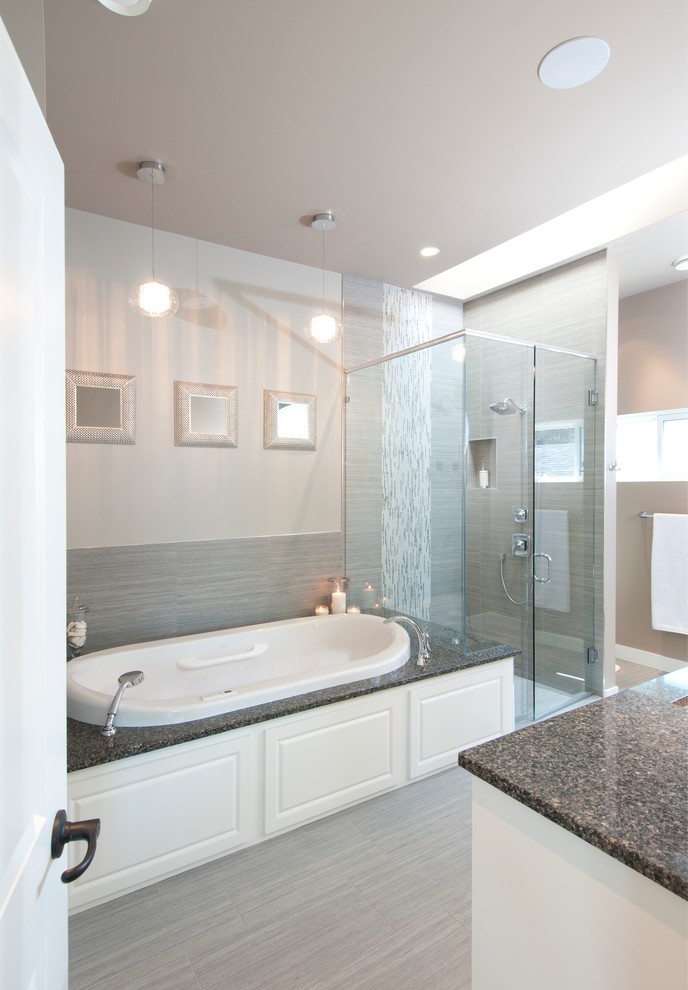 Photo of a large contemporary ensuite bathroom in Vancouver with a submerged sink, raised-panel cabinets, white cabinets, engineered stone worktops, a built-in bath, a shower/bath combination, a two-piece toilet, grey tiles, porcelain tiles, grey walls and porcelain flooring.
