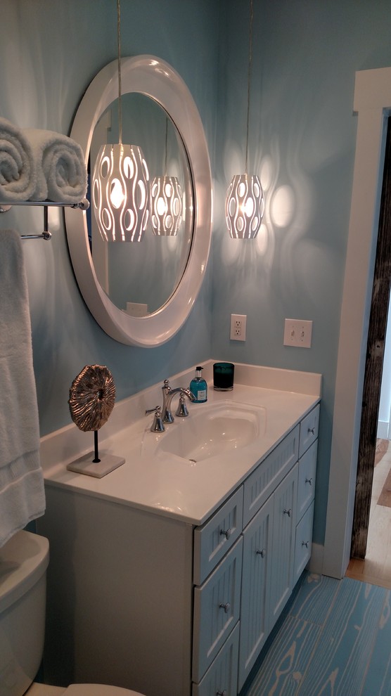 Bild på ett stort maritimt badrum med dusch, med skåp i shakerstil, vita skåp, en dusch i en alkov, en toalettstol med separat cisternkåpa, vit kakel, porslinskakel, blå väggar, målat trägolv, ett integrerad handfat, bänkskiva i kvarts, blått golv och dusch med skjutdörr