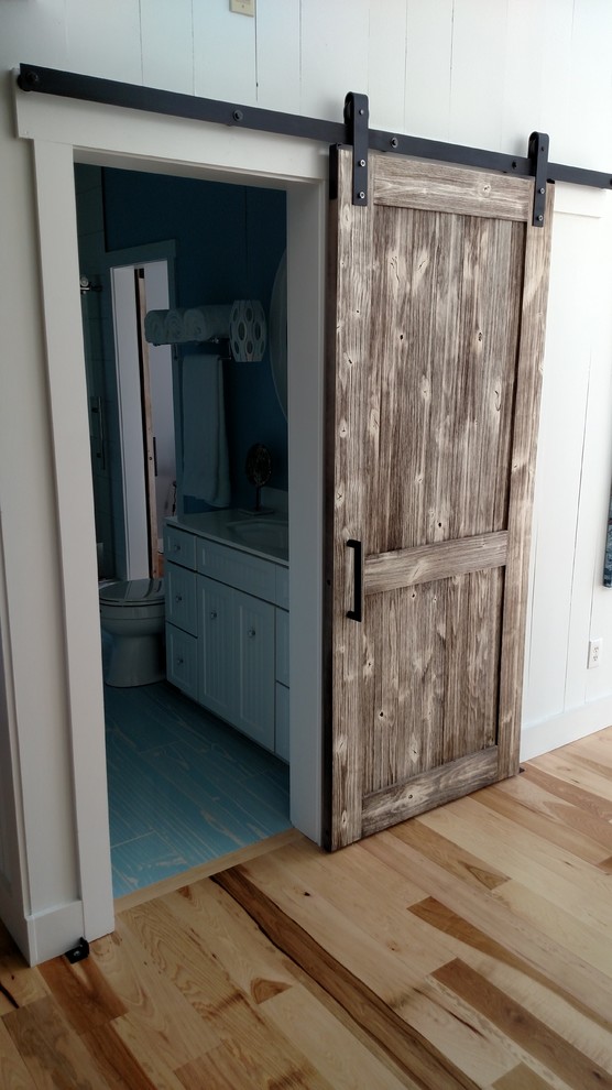 Идея дизайна: большая ванная комната в морском стиле с фасадами в стиле шейкер, белыми фасадами, душем в нише, раздельным унитазом, белой плиткой, керамогранитной плиткой, синими стенами, деревянным полом, душевой кабиной, монолитной раковиной, столешницей из искусственного кварца, синим полом и душем с раздвижными дверями