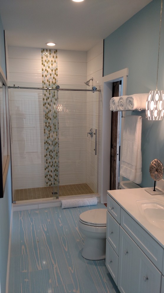 На фото: большая ванная комната в морском стиле с фасадами в стиле шейкер, белыми фасадами, душем в нише, раздельным унитазом, белой плиткой, керамогранитной плиткой, синими стенами, деревянным полом, душевой кабиной, монолитной раковиной, столешницей из искусственного кварца, синим полом и душем с раздвижными дверями