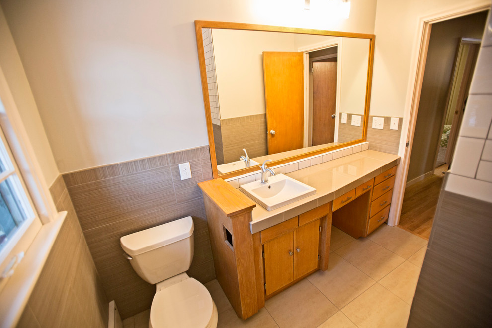 Cette image montre une salle de bain design en bois clair avec un placard à porte plane, une baignoire d'angle, une douche d'angle et un carrelage blanc.