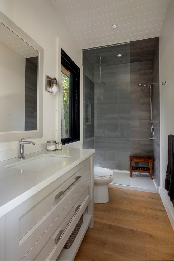 Exempel på ett mellanstort modernt vit vitt badrum med dusch, med luckor med infälld panel, vita skåp, en dusch i en alkov, vit kakel, vita väggar, ljust trägolv, ett nedsänkt handfat, granitbänkskiva, brunt golv och med dusch som är öppen