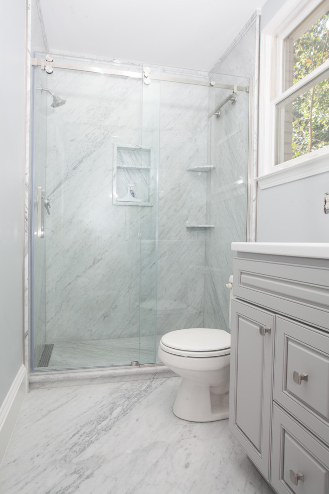 Bild på ett stort vintage vit vitt en-suite badrum, med luckor med upphöjd panel, grå skåp, en dusch i en alkov, en toalettstol med hel cisternkåpa, stenhäll, blå väggar, marmorgolv, ett integrerad handfat, bänkskiva i akrylsten, grått golv och dusch med skjutdörr