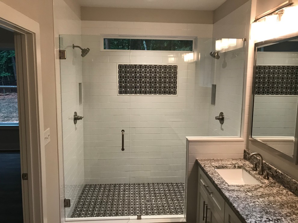 Bild på ett amerikanskt flerfärgad flerfärgat en-suite badrum, med skåp i shakerstil, vita skåp, en kantlös dusch, vit kakel, keramikplattor, grå väggar, mosaikgolv, ett undermonterad handfat, granitbänkskiva, svart golv och dusch med gångjärnsdörr