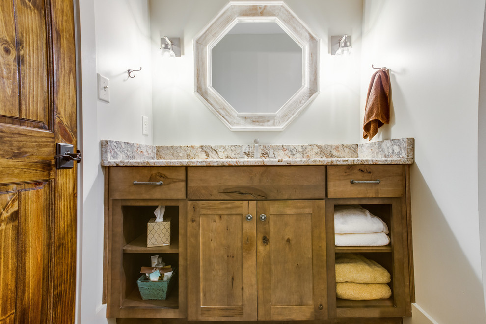 Exemple d'une salle de bain montagne en bois brun de taille moyenne avec un placard à porte shaker et un plan de toilette en granite.