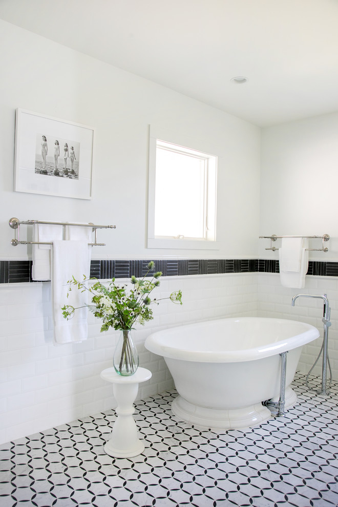 This is an example of a large farmhouse ensuite bathroom in Other with flat-panel cabinets, white cabinets, a freestanding bath, a built-in shower, a one-piece toilet, ceramic tiles, white walls, ceramic flooring, a vessel sink, engineered stone worktops, white floors, a hinged door and black worktops.